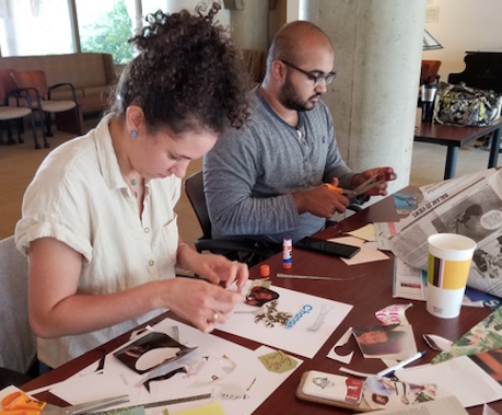 Two people sitting at a table working on collages